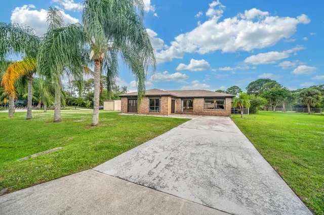 a view of house with a big yard and palm trees