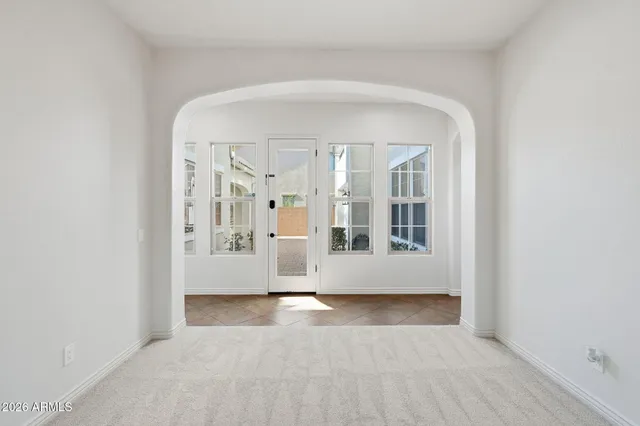 an empty room with chandelier fan and windows