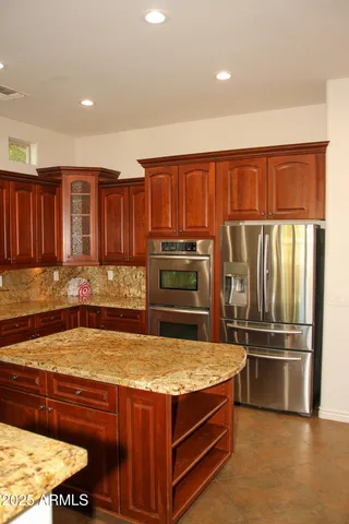 a kitchen with stainless steel appliances kitchen island granite countertop a refrigerator and a sink