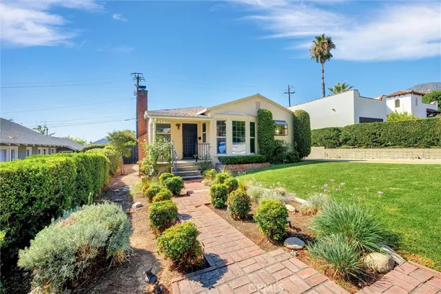a front view of a house with a yard and potted plants