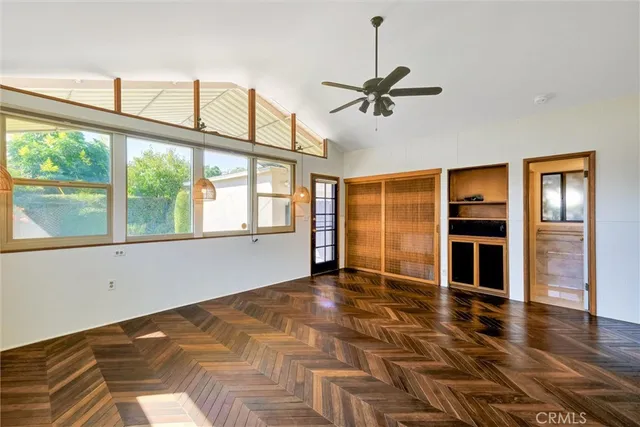 a view of an empty room with a window and wooden floor
