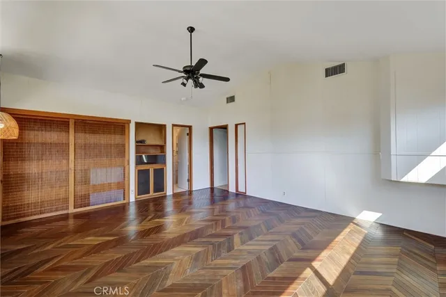 a view of a room with a ceiling fan window and wooden floor