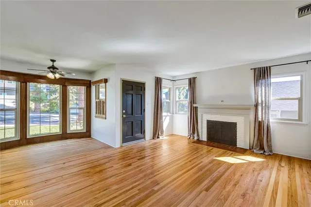 a view of an empty room with window and wooden floor
