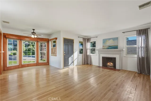 a view of an empty room with wooden floor fireplace and a window