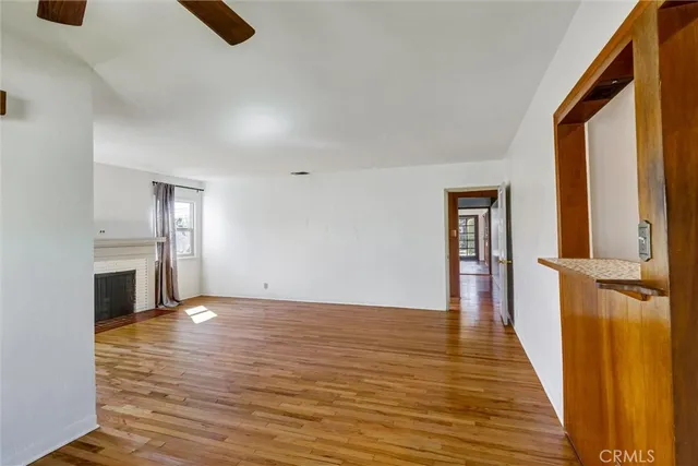 a view of an empty room with window and wooden floor