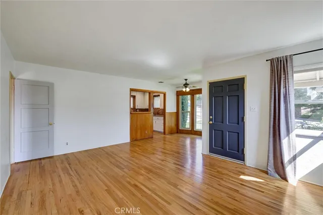 a view of empty room with wooden floor and fan