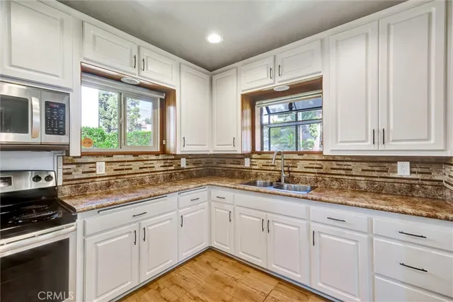 a kitchen with granite countertop white cabinets and a window