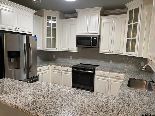 a kitchen with granite countertop a sink stove and refrigerator