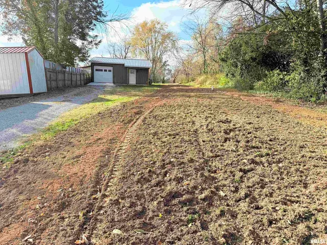 a view of yellow house with a yard and large trees