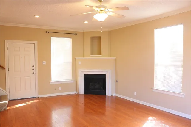 a view of an empty room with window and wooden floor