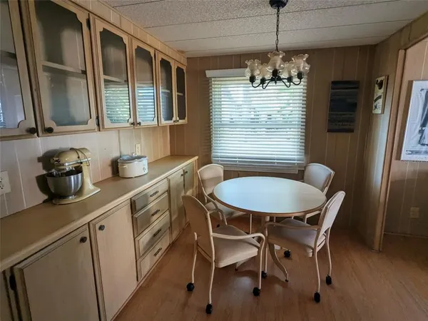 a kitchen with stainless steel appliances granite countertop white cabinets a refrigerator a sink a stove and a dining table with wooden floor