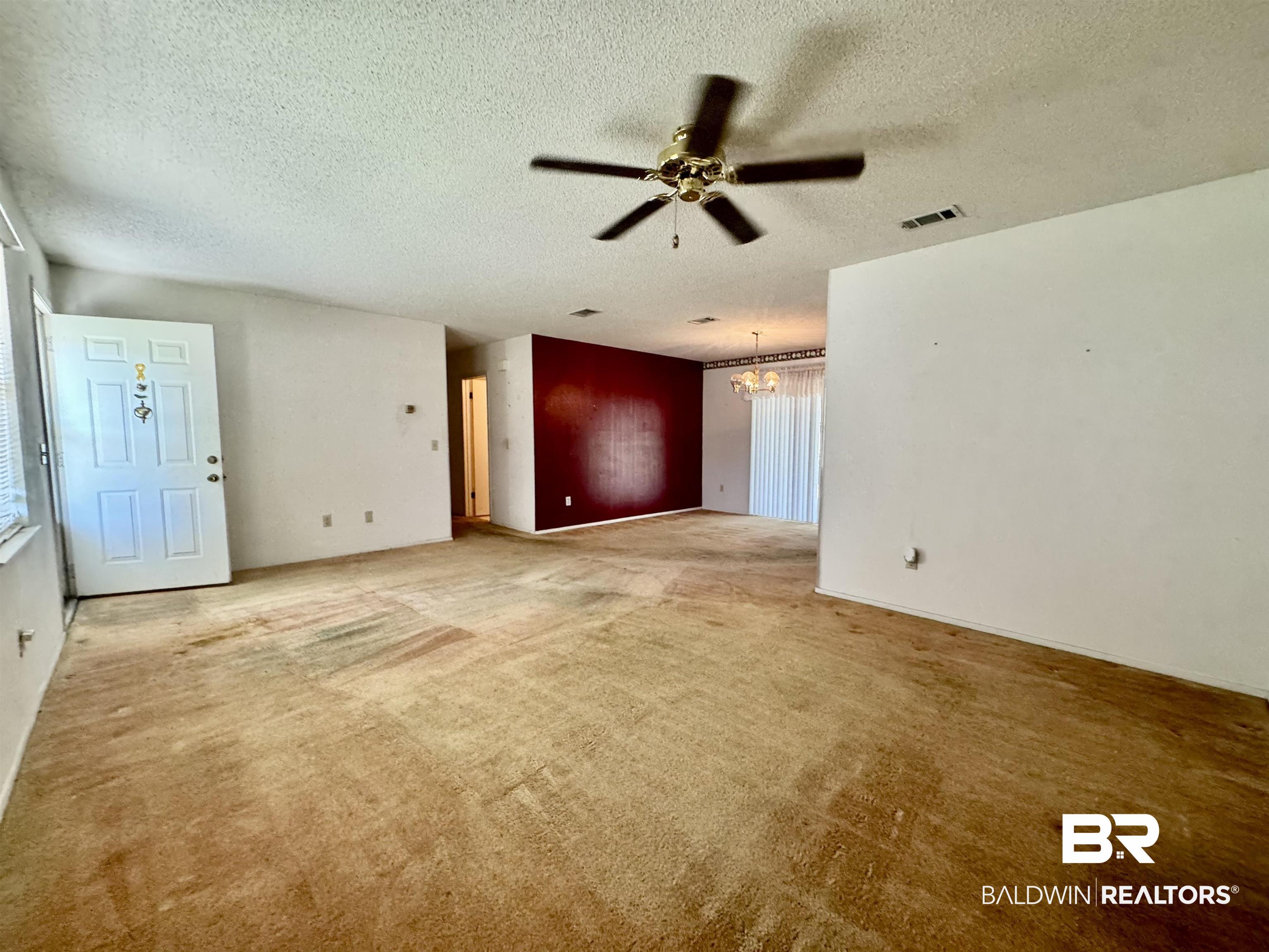 512 Deborah Court Foley, AL 36535 - Photo 13 of 23 Unfurnished living room featuring a textured ceiling, ceiling fan with notable chandelier, and a wealth of natural light