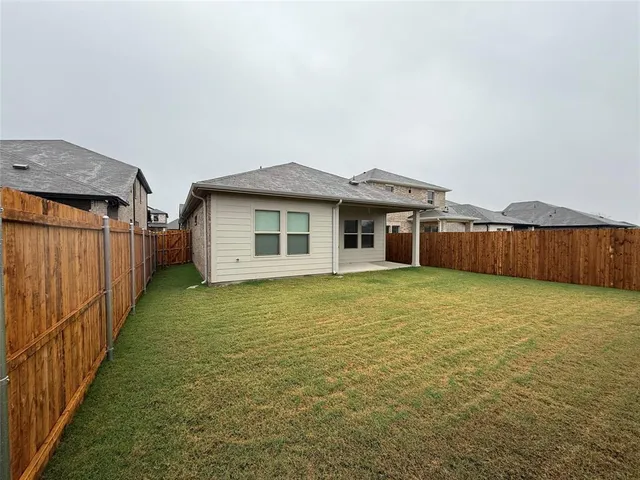 a view of a house with backyard and wooden fence
