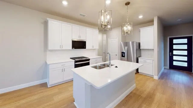 a large white kitchen with a sink a refrigerator and a stove top oven