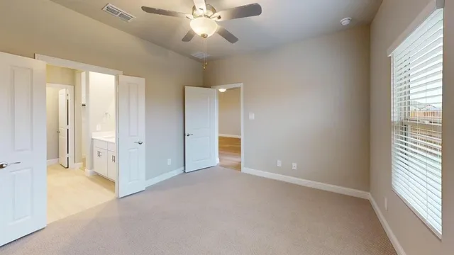 an empty room with chandelier fan and windows