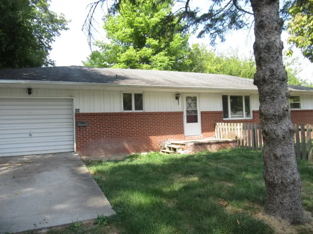 a backyard of a house with table and chairs plants and large tree