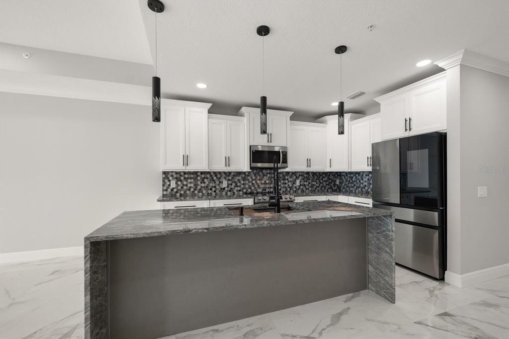 211 Dolphin Point, Unit 301 Clearwater, FL 33767 - Photo 13 of 48 a kitchen with stainless steel appliances granite countertop a sink a refrigerator and a stove