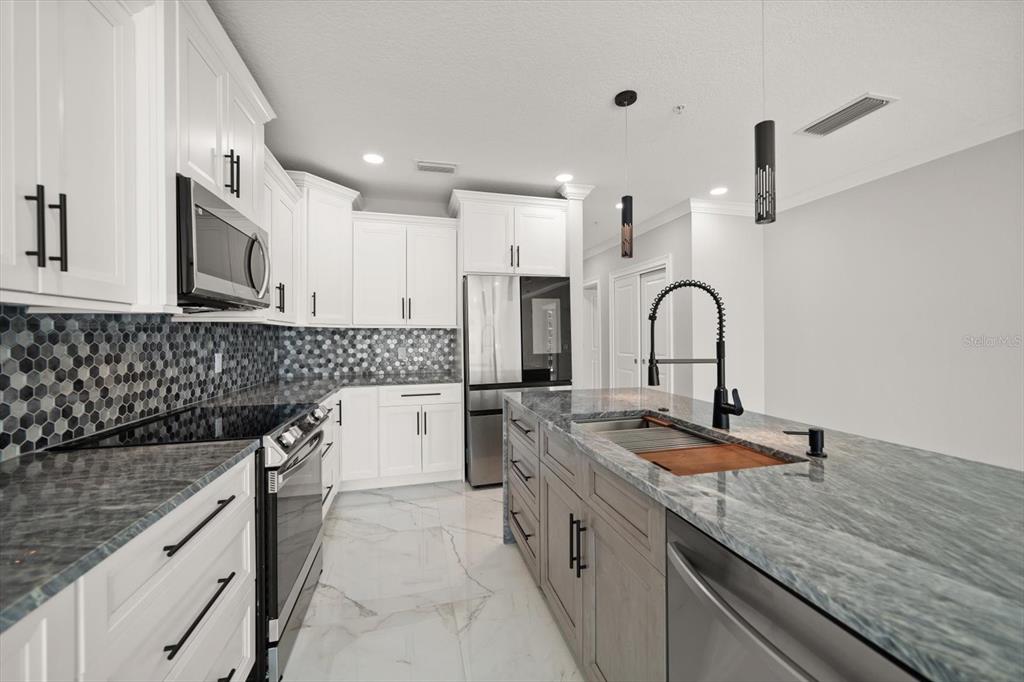 211 Dolphin Point, Unit 301 Clearwater, FL 33767 - Photo 6 of 48 a kitchen with granite countertop a sink stainless steel appliances and white cabinets