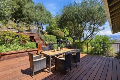 a view of a backyard with couches plants and large trees
