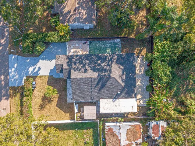 an aerial view of a house with a yard and large trees