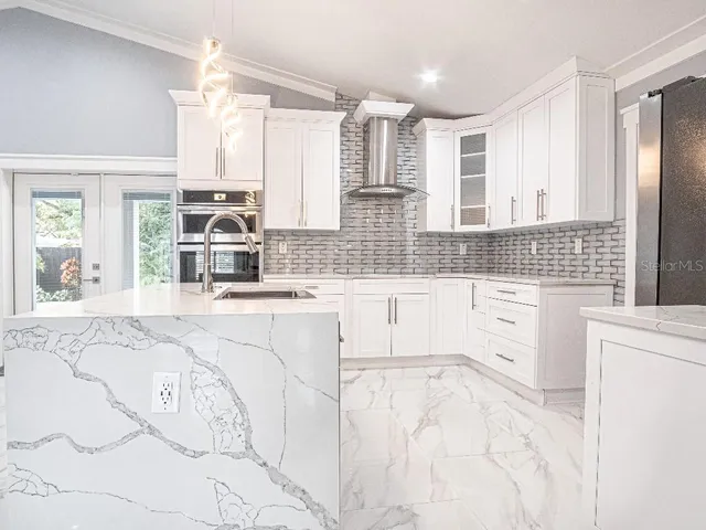 a large white kitchen with granite countertop a sink white cabinets and a granite counter tops