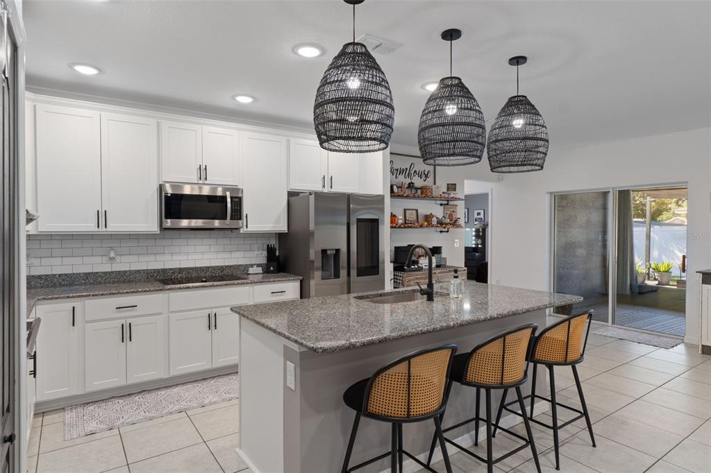 3313 Dorian Avenue Spring Hill, FL 34606 - Photo 4 of 57 a kitchen with stainless steel appliances granite countertop a kitchen island a stove cabinets a dining table and chairs