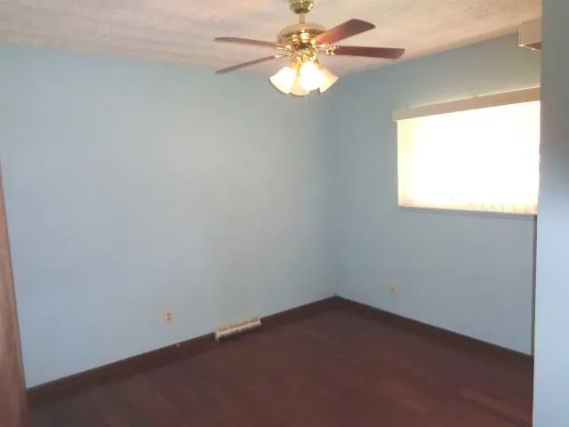 an empty room with a window and a fan