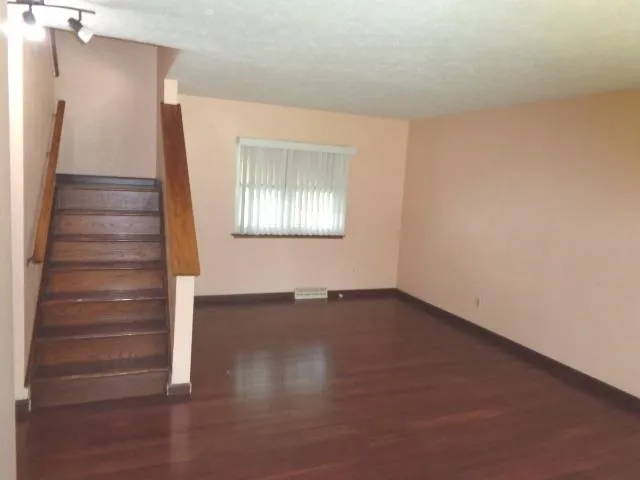 a view of an empty room with wooden floor and windows