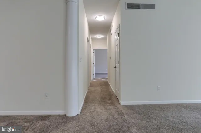 a view of a hallway with wooden floor and a bathroom