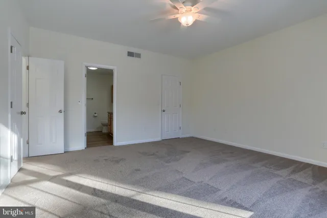 an empty room with a chandelier fan and entryway