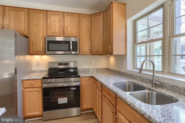 a kitchen with granite countertop a sink stainless steel appliances and cabinets
