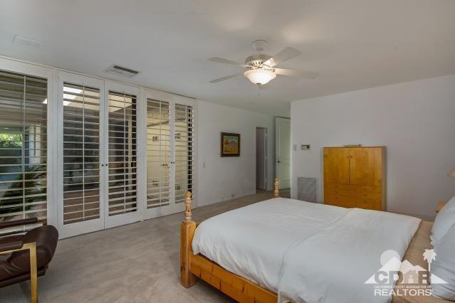6 Exeter Court Rancho Mirage, CA 92270 - Photo 15 of 20 a bedroom with a bed and a chandelier