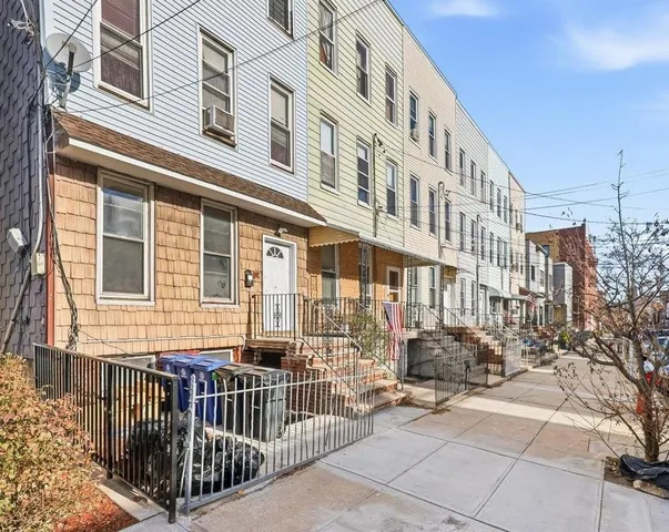 a view of a building with a small yard and large tree