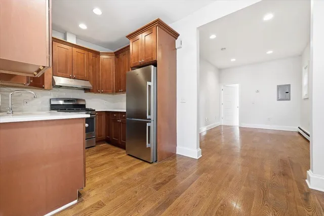 a kitchen with stainless steel appliances granite countertop a refrigerator a sink a stove and oven