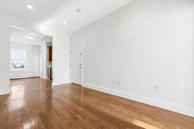 an empty room with wooden floor and natural light