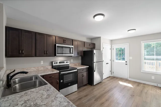 a kitchen with a sink wooden floor and a refrigerator