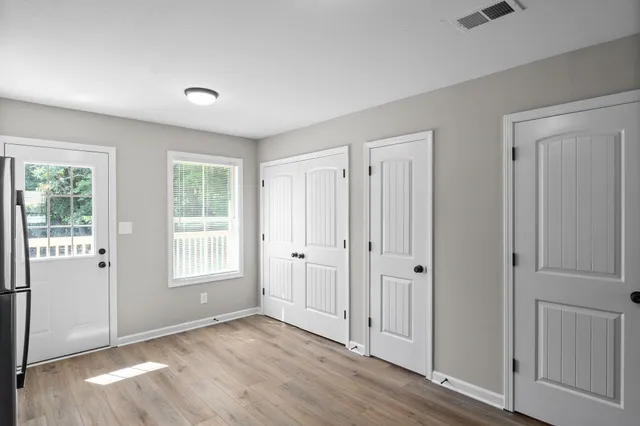 an empty room with wooden floor and windows