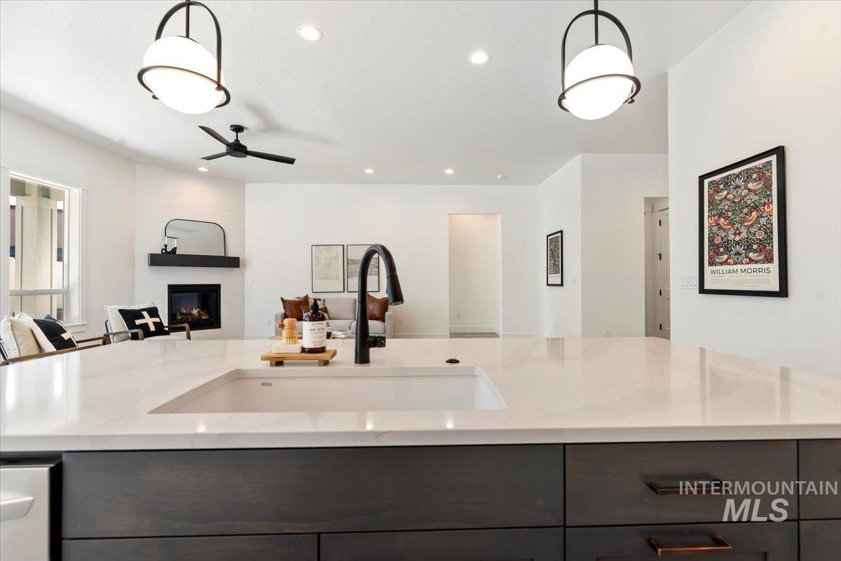 2391 East Snocreek Drive Eagle, ID 83616 - Photo 29 of 29 Kitchen with gray cabinetry, open floor plan, recessed lighting, light stone counters, and hanging light fixtures