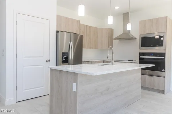 a view of a kitchen with kitchen island a sink stainless steel appliances and cabinets