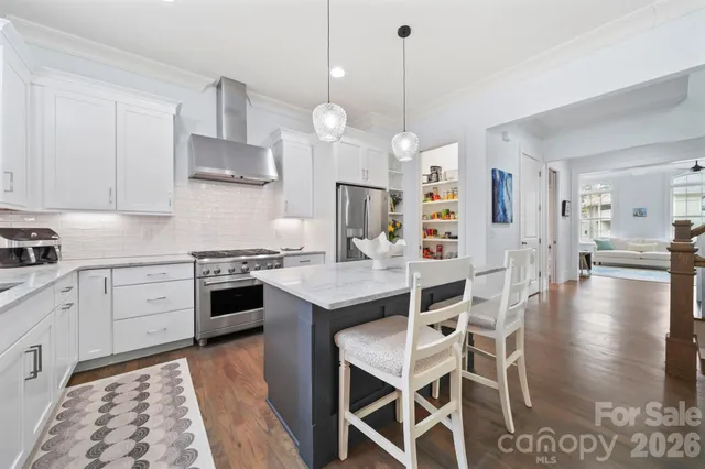 a kitchen with stainless steel appliances kitchen island granite countertop a stove a sink a dining table and chairs with wooden floor