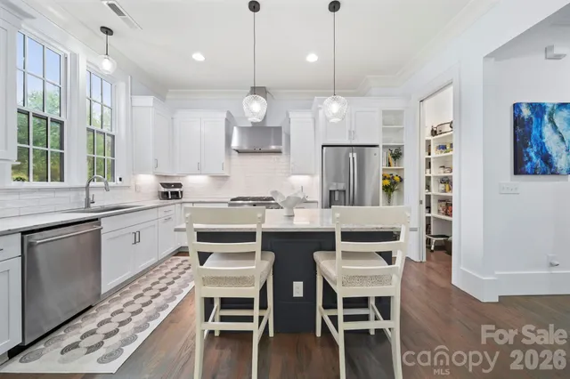 a kitchen with a dining table chairs wooden floor cabinets and stainless steel appliances