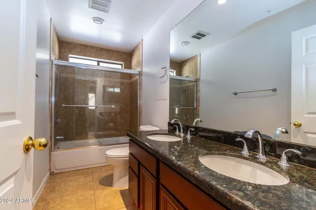 a bathroom with a granite countertop sink mirror bathtub and toilet