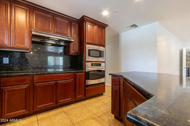 a kitchen with stainless steel appliances granite countertop a refrigerator and a stove top oven