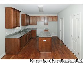 Lot 12 Booth Pond Road Raeford, NC 28376 - Photo 5 of 11 a kitchen with kitchen island granite countertop wooden cabinets a sink and a stove