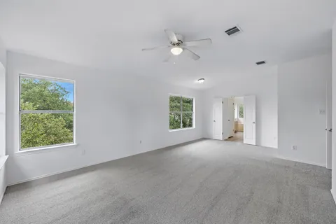 an empty room with windows and fan