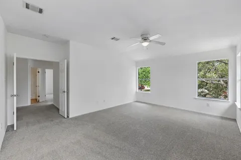 an empty room with windows and fan