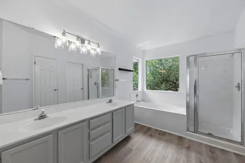 a spacious bathroom with a double vanity sink a large mirror and a bathtub
