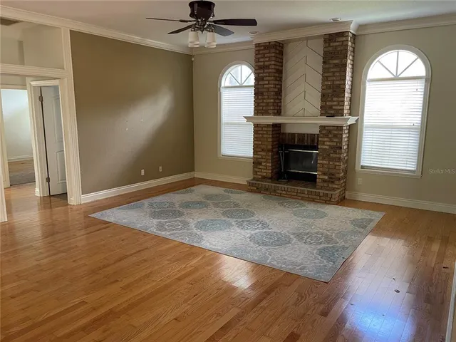 an empty room with windows fireplace and wooden floor