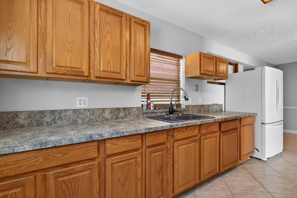 a view of empty room with wooden floor and kitchen