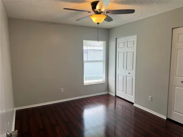 an empty room with wooden floor closet and windows